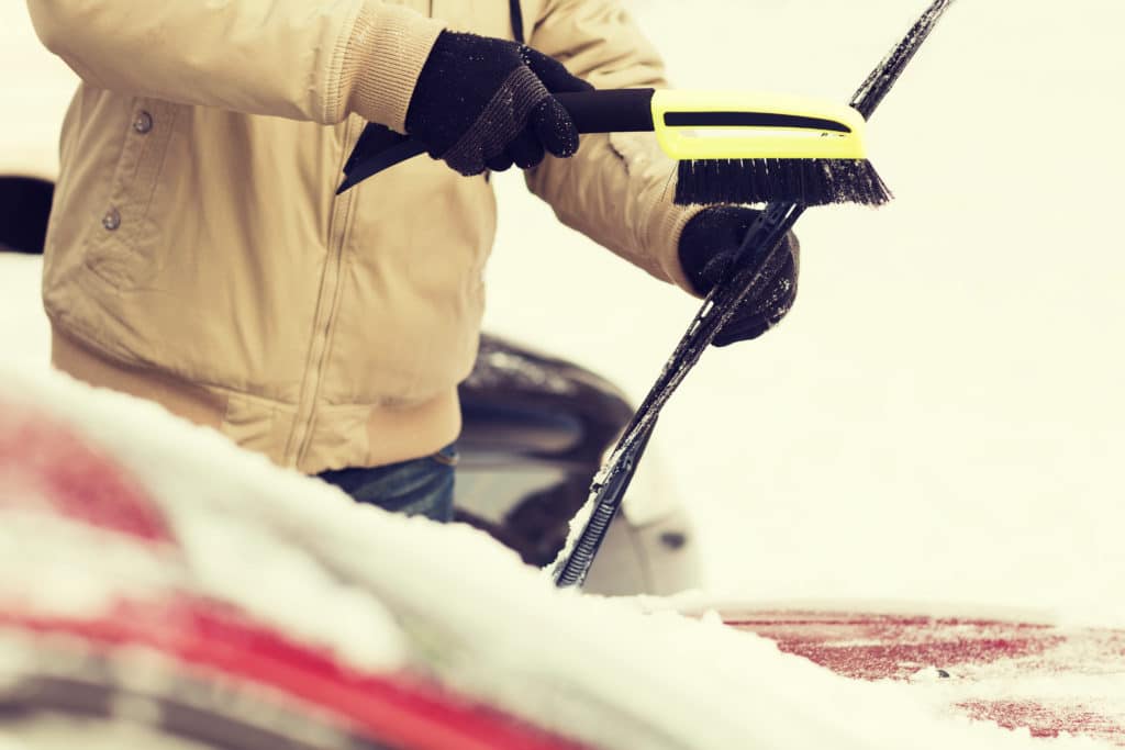 scraping snow off windshield in winter