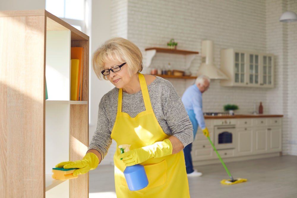 Elderly couple wearing bright yellow cleaning their kitchen